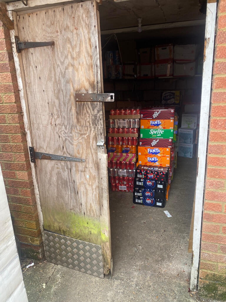 Two wooden outdoor storeroom doors being rebuilt with new hinges and lock installation in progress