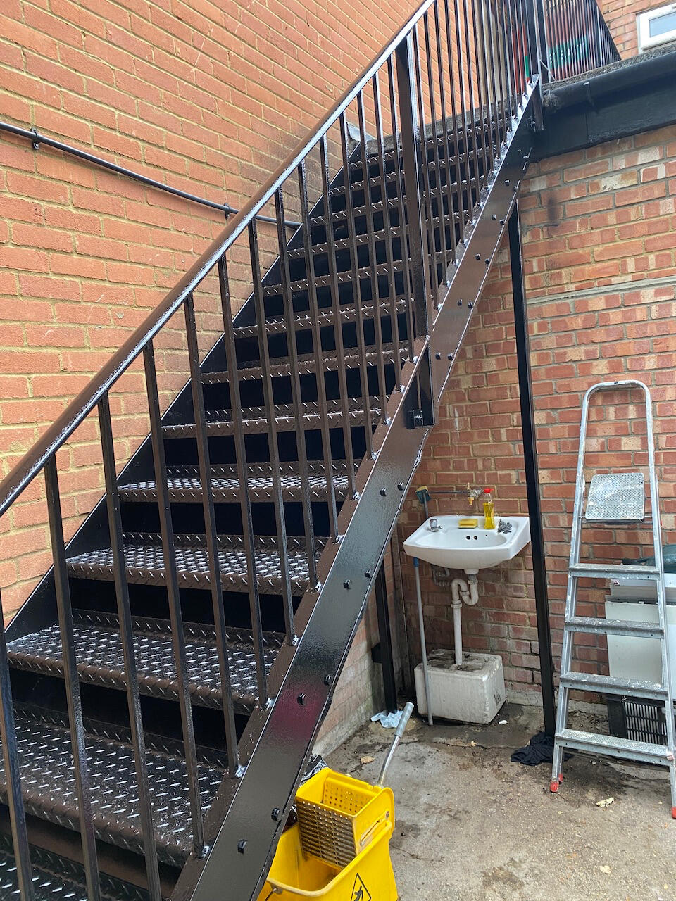 Rusty fire exit metal stairs fully prepared and painted with black metal paint for a clean finish.